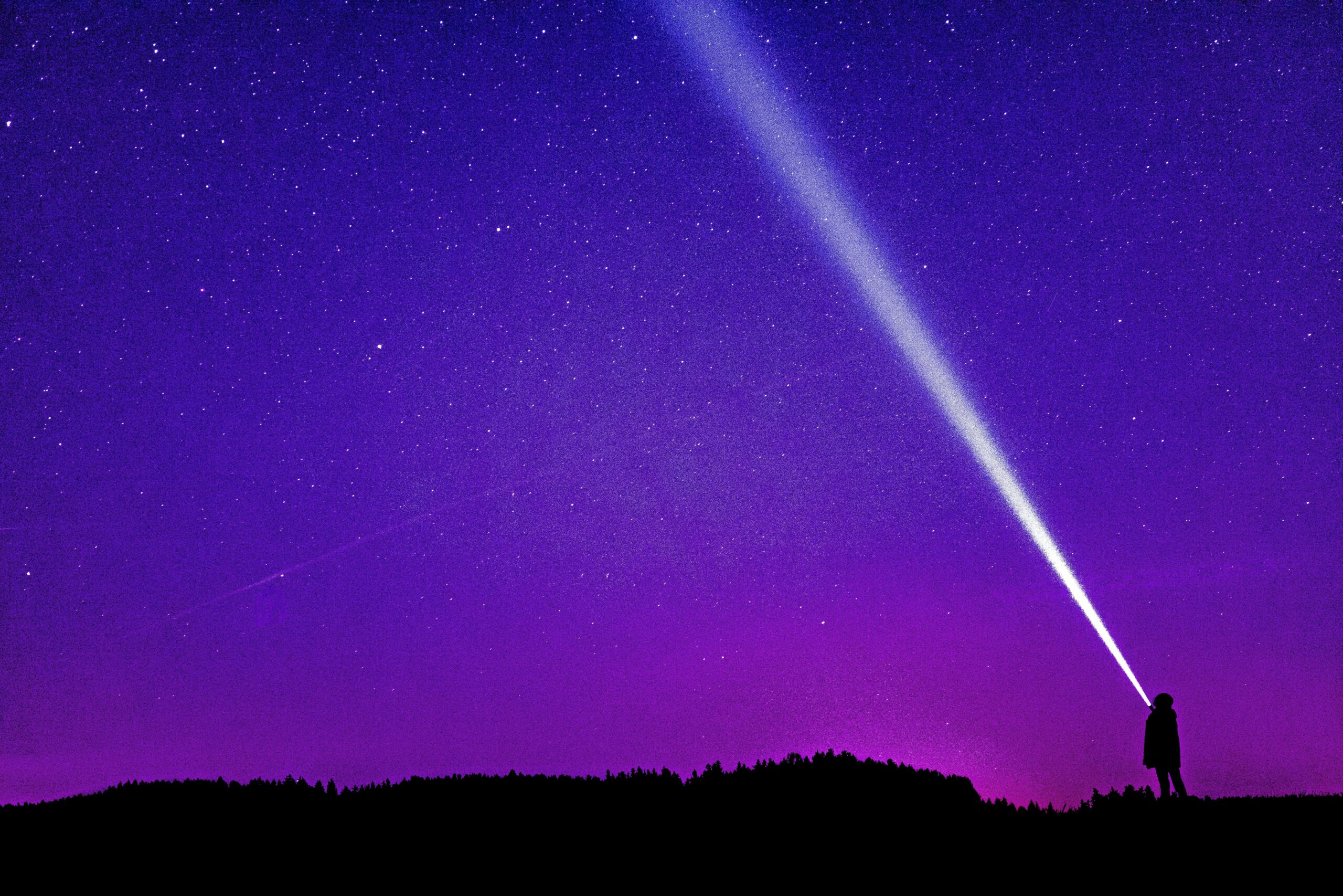 Silhouette of a person shining a flashlight under a starry violet night sky, creating a dramatic scene.